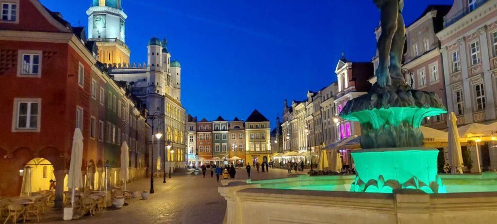 the old town square in poznan at night with a green lid fountain