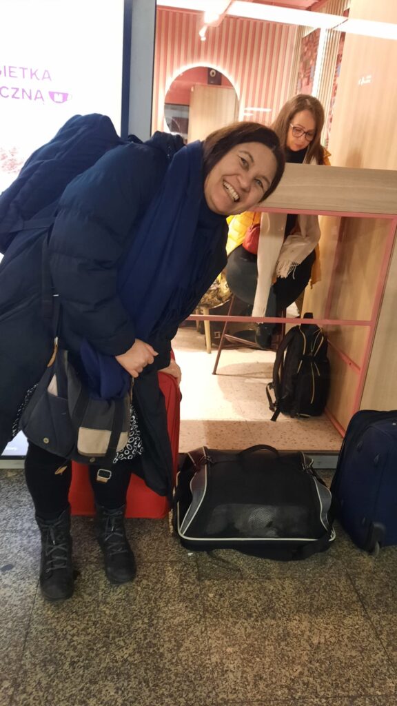 Karen standing with Sofus the dog and luggage on the platform at Warsaw Central station.